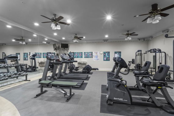 Indoor gym with exercise equipment and mirrors on the walls.