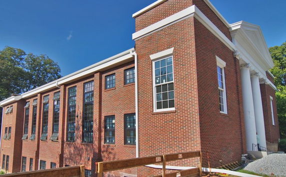Brick building with large windows and white columns at the front.