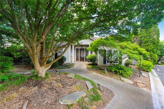 Front view of a single-story house with a pathway and surrounding trees.
