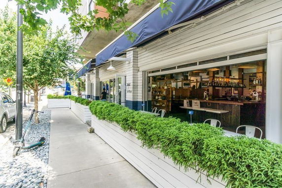 Front view of a building with outdoor seating and greenery.