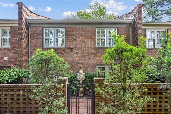 Front view of a two-story brick house with windows and gated entrance.