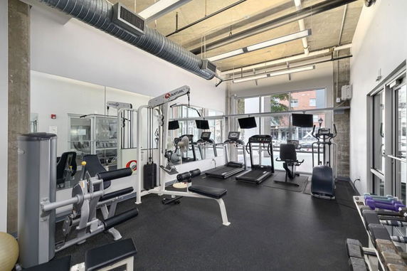 Interior view of a fitness gym with exercise equipment including treadmills and weight machines.