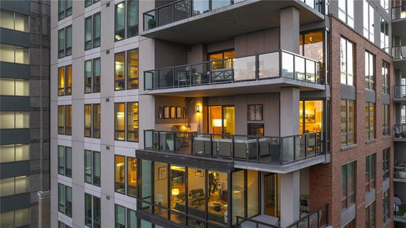 Front view of a multi-story building with glass balconies and illuminated interiors.