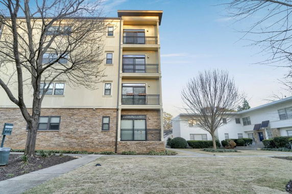 Front view of a multi-story apartment building with balconies and stone accents.