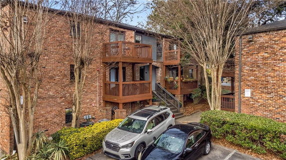 Front view of a multi-story brick apartment building with balconies and parked cars.