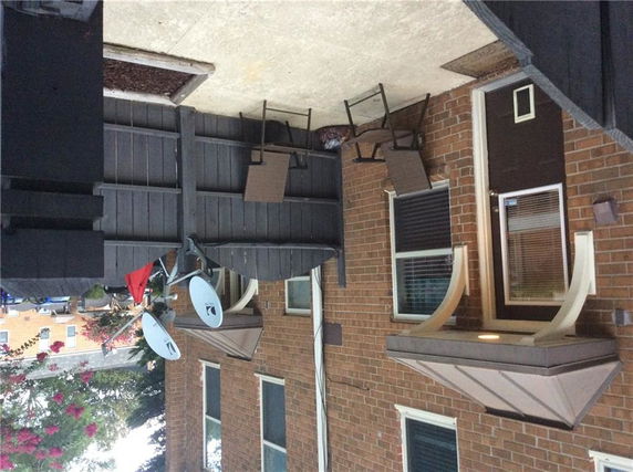 Front view of a brick house with two satellite dishes and a small porch.