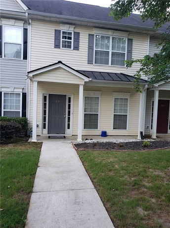 Front view of a two-story townhouse with a small porch and two windows on the lower level.