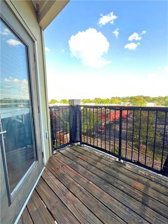 View of surrounding areas from a balcony with wooden flooring and metal railing.