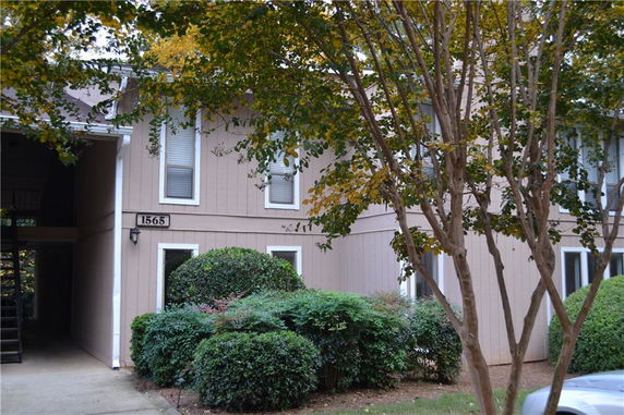 Front view of a two-story building with a side entrance and foliage.