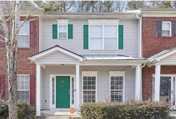 Front view of a two-story townhouse with green shutters and a green door.
