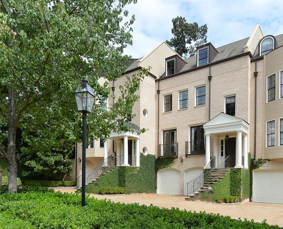 Front view of a multi-story townhouse with garages and columns.