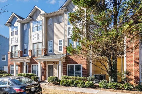 Front view of a three-story townhouse with brick and siding exterior.