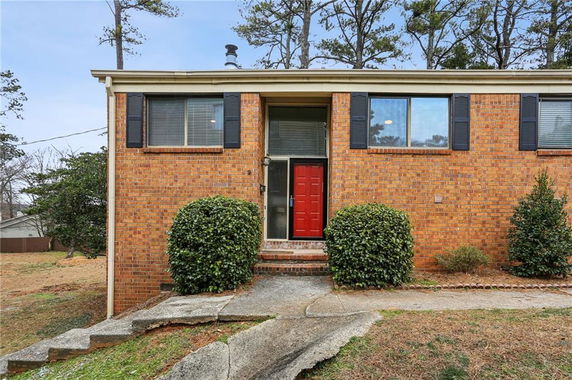 Front view of a single-story house with red door and brick exterior.