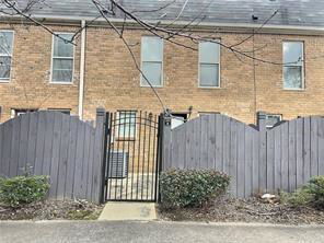 Front view of a two-story brick building with a gated entrance and wooden fence.