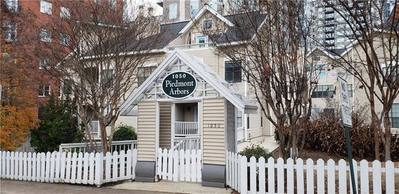 Front view of a multistory building with distinctive architectural elements and a white picket fence.