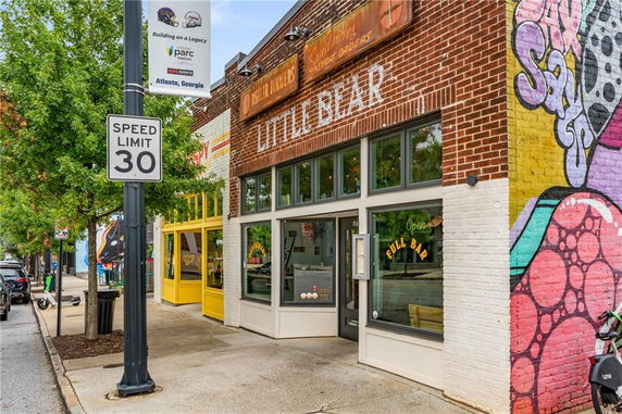 Front view of a brick building with large windows and colorful mural artwork.