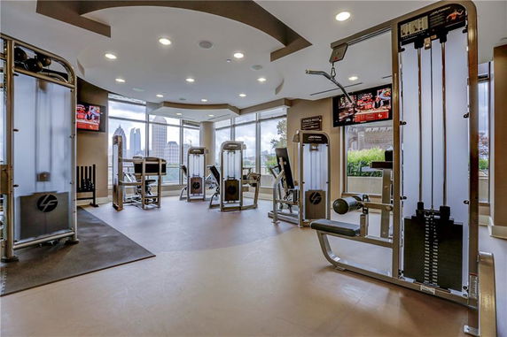 Interior view of a fitness room with exercise equipment and large windows.