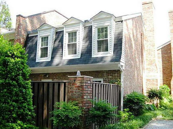 Front view of a brick two-story house with dormer windows.