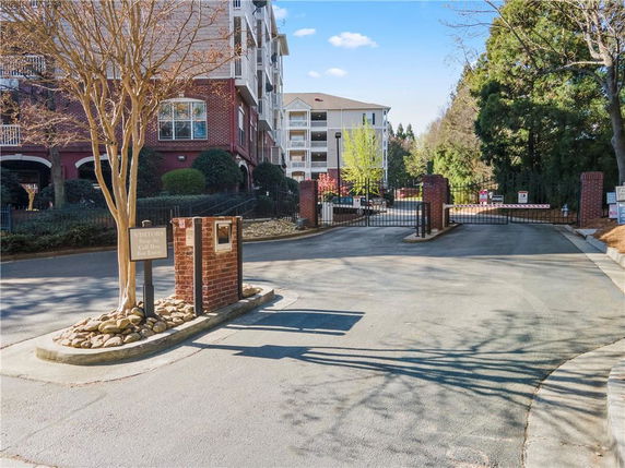 Gated entrance to an apartment complex with surrounding trees.