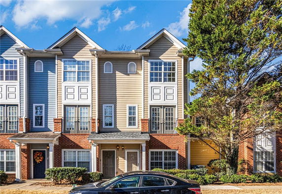 Front view of a multi-story townhouse with brick and siding exterior.