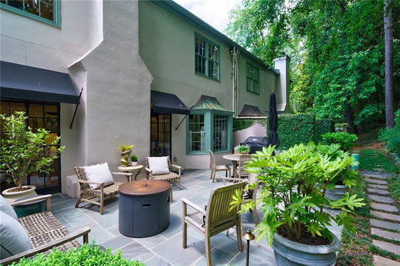 Front view of a house with a patio area, featuring outdoor furniture and potted plants.