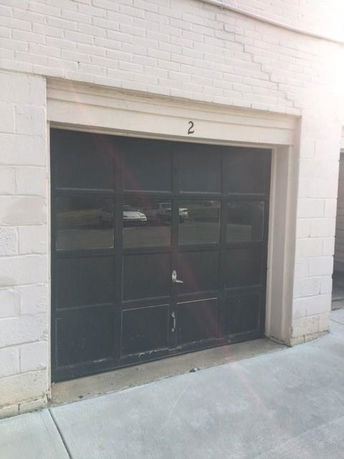 Front view of a building entrance with a closed black garage door.