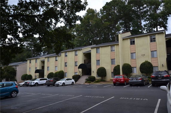 Front view of a multi-story apartment building with parking area.