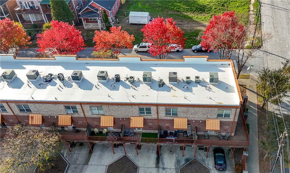 Aerial view of a building with multiple rooftop air conditioning units and a parking area below.