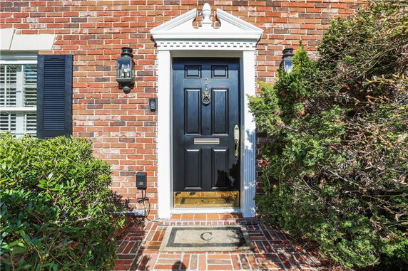Front view of a brick house entrance with a black door and sidelights.