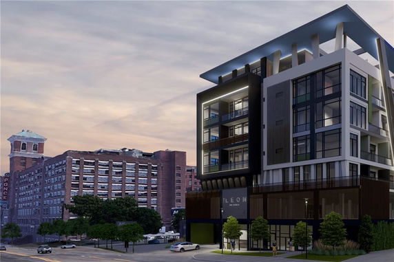 Front view of a modern multi-story building with large windows and balconies, adjacent to an older industrial-style building.