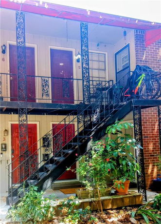 Front view of a building with an exterior iron staircase and multiple red doors.