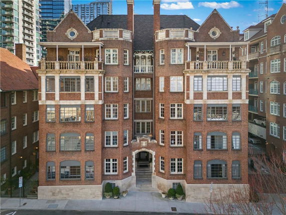 Front view of a multi-story brick building with ornate balconies and large windows.