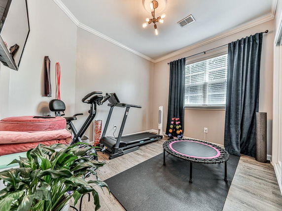 Room equipped with exercise equipment including a treadmill and a mini trampoline.