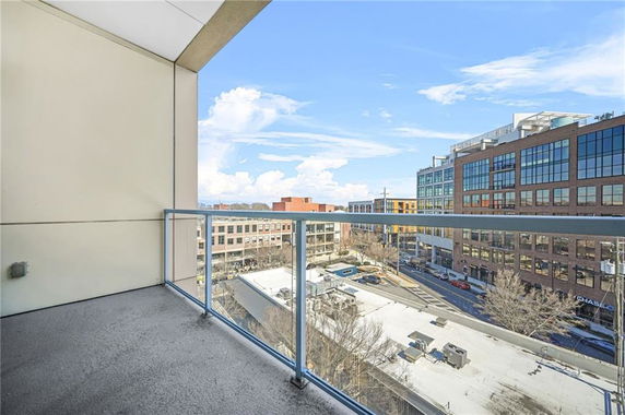 Viewing from a balcony, overlooking an urban area with modern buildings and a street.