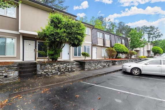 Front view of a row of two-story townhouses with a stone retaining wall.