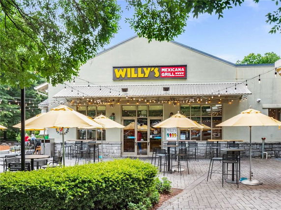 Front view of a restaurant building with outdoor seating and umbrellas.
