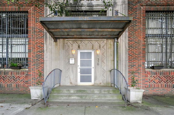 Front view of a brick building entrance with metal canopy and steps.