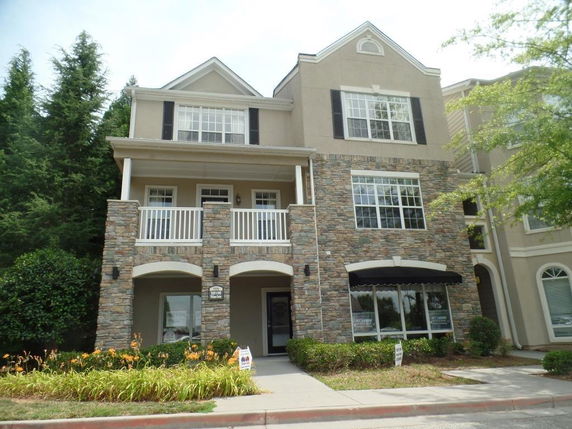Front view of a multi-story house with a stone facade and balcony.
