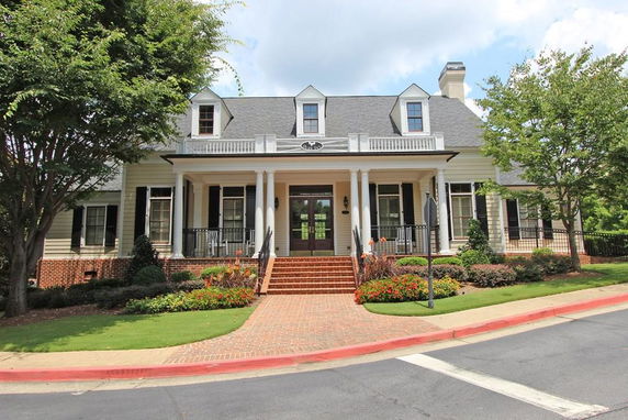 Front view of a two-story house with a porch and dormer windows.