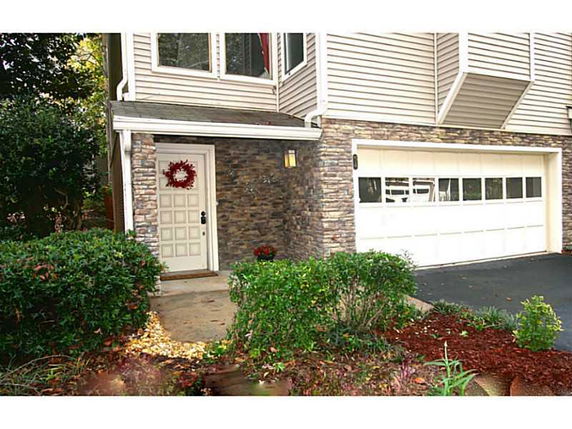 Front view of a house with stone facade and a white garage door.