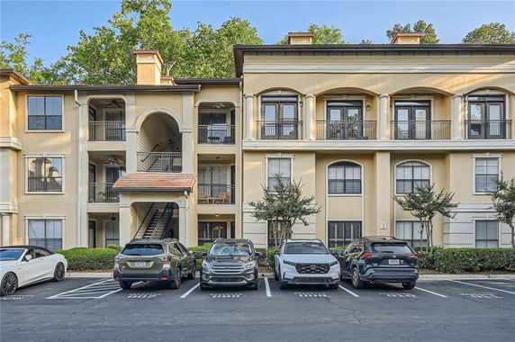 Front view of a three-story building with balconies and parking area.