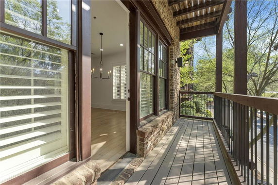 View from a balcony of a brick house, looking out over trees and street.