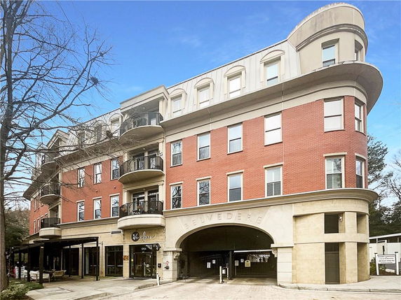 Front view of a multi-story building with rounded corners and a passageway entrance.
