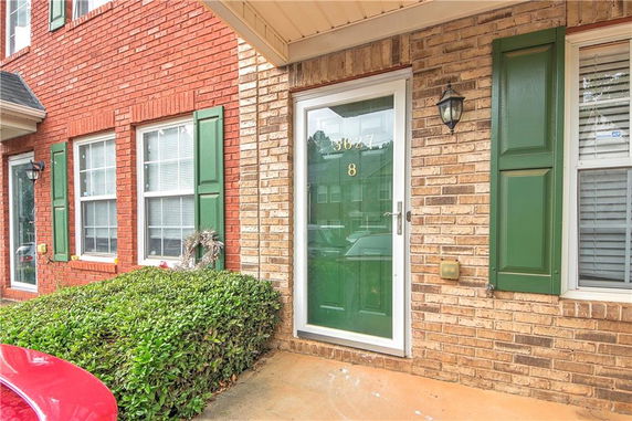Front view of a brick house with green shutters and a green front door.