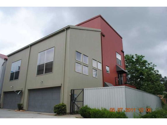 Front view of a modern multi-story building with large windows and a corrugated exterior.