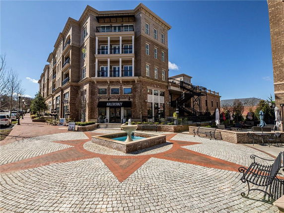 Front view of a multi-story brick building with a central fountain in the courtyard.