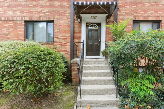 Front view of a brick building with a central entrance and steps leading to a door.