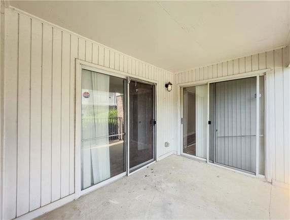 Covered outdoor area with sliding glass doors and wood panel walls.