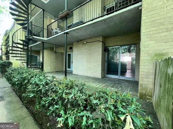 Rear view of a two-story building with balconies and spiral staircase.