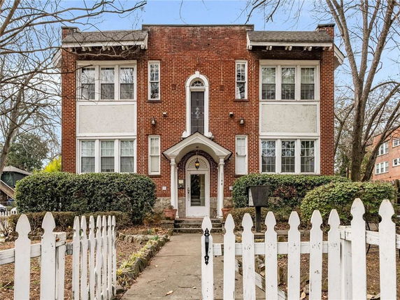 Front view of a two-story brick house with white trim and multiple windows.